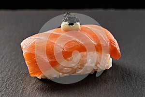 Sake nigiri sushi topped with sauce and black caviar. photo