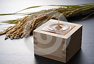 Sake is poured into the black background. Ears of rice on the background