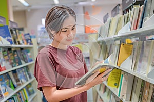 Sakon Nakhon, Thailand-August 5, 2023: Unidentified happy young woman woman shopping and choosing books in the bookstore