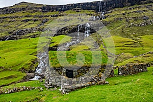 Saksun typical Faroe Islands house under the waterfall