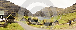 Saksun village surrounded by green landscapes and moss covered houses in a Fjord on the Faroe Islands in Denmark.