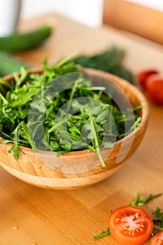 Salad with arugula cherry tomatoes and cucumbers in a wooden Bowl on a wooden table.