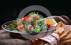 Salad with arugula and cherry tomatoes with shrimp, slices of lemon and parmesan