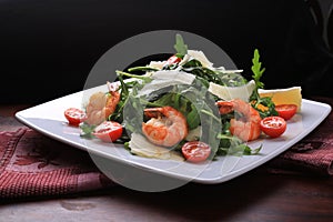 Salad with arugula and cherry tomatoes with shrimp, slices of lemon and parmesan
