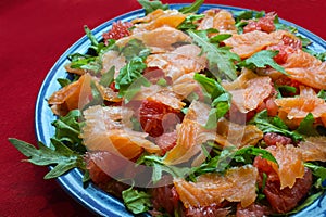 Salad with arugula, grapefruit and salmon on a red tablecloth, a