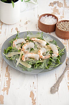 Salad with arugula, shrimps, parmesan cheese and pine nuts