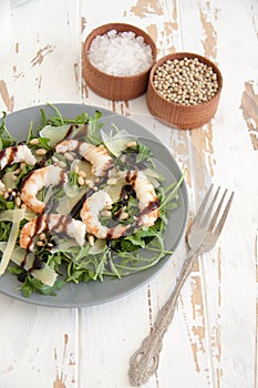 Salad with arugula, shrimps, parmesan cheese and pine nuts