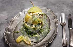 Salad with arugula stracciatella nuts grapes and honey in pear on metal plate on black background