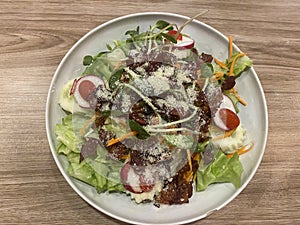 Salad bacon serving on white plate on wooden table