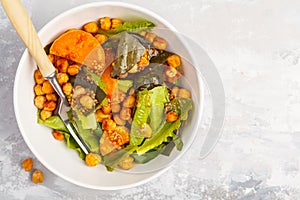 Salad with baked pumpkin and chickpeas with mustard-honey dressing in a white plate, top view. Healthy vegan food concept.