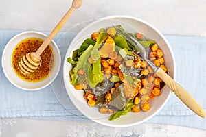 Salad with baked pumpkin and chickpeas with mustard-honey dressing in a white plate, top view. Healthy vegan food concept.