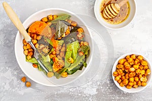 Salad with baked pumpkin and chickpeas with mustard-honey dressing in a white plate, top view. Healthy vegan food concept.