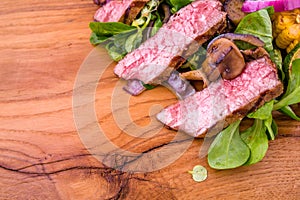 Salad with beef slices, grilled vegetables - eggplant, corn, mushrooms, sauce on a wooden board, dish