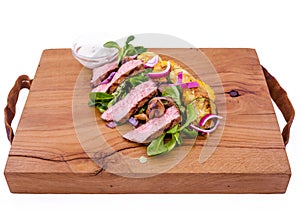 Salad with beef slices, grilled vegetables - eggplant, corn, mushrooms, sauce on a wooden board, dish. The object is isolated on a