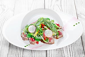 Salad with beef steak, baby spinach, lettuce, sweet pepper and grains of pomegranate on wooden background close up
