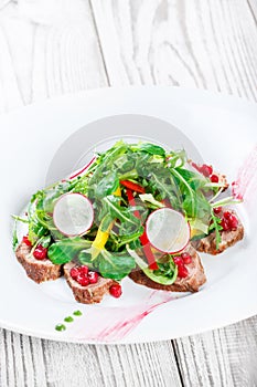 Salad with beef steak, baby spinach, lettuce, sweet pepper and grains of pomegranate on wooden background close up