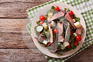 Salad with beef steak, cheese and vegetables dressed with chimic