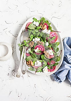 Salad with beets, arugula, feta cheese and walnuts. On a light background