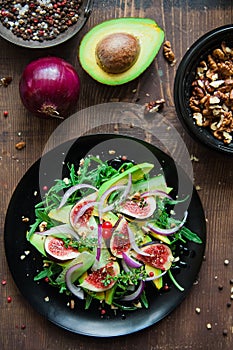 salad on a black plate: arugula, figs, avocado, red onions, cucumbers, walnuts, viburnum, thyme