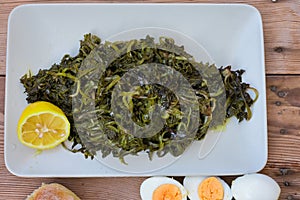 salad with boiled wild greens, dandelion, lemons and extra virgin olive oil. Horta or Wild Greens. Greek Cuisine.