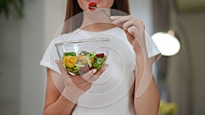 Salad bowl in hand of unrecognizable blurred woman tasting delicious healthful dinner in slow motion. Caucasian slim