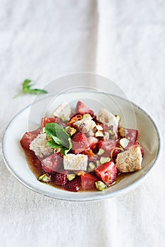 Salad bowl with strawberries, tomatoes, pistachios and croutons in honey orange oil sauce