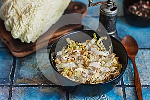 Salad with cabbage, eggs, corns and meat on the plate on rustic tiled table