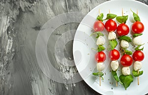 Salad Caprese - shish kebab with tomato, mozzarella and basil, Italian cuisine and a healthy vegetarian diet on a dark background.