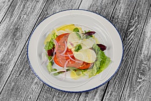 Salad with cheese and tomatoes on wooden background. The view from the top
