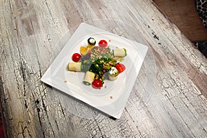 Salad with cherry tomatoes, cucumbers and orange on wood table