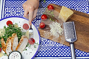 Salad with chicken Caesar salad with micro-greens, cherry tomatoes and parmesan on a blue ornament background