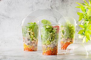 Salad with chicken, tomatoes, carrots and corn in plastic tare. Chicken salad with vegetables.  on white marble background