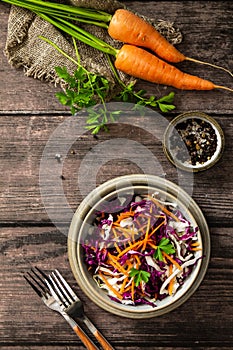 Salad Cole Slaw. Autumn Cabbage salad in a bowl on a rustic wooden table. Flat lay top view.