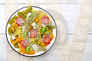 Salad with colorful pasta, cherry tomatoes, feta cheese and fresh basil