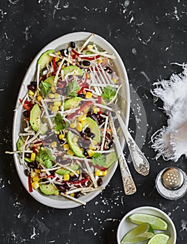 Salad with corn, beans, avocado and tortilla. Mexican black bean salad. On a dark background