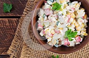 Salad with corn and crab sticks in bowl on wooden table