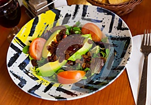 Salad with cornsalad, avocado, raisins and strawberry jam