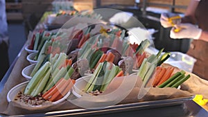 Salad in disposable plates at the baffet. waiter cooking Carrots cucumbers dill with sauce.