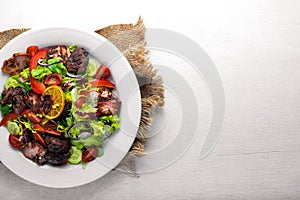 Salad with fresh cucumbers, tomatoes and greens with grilled meat on a plate Wooden board.