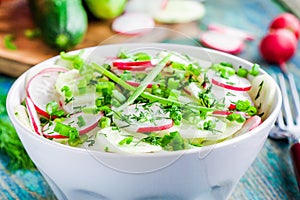 Salad of fresh organic radish and cucumber in white bowl closeup