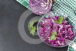 Salad of fresh red cabbage with herbs, fresh head of cabbage, 1 gray plate vegetable vitamin salad on a towel in a cage on a black