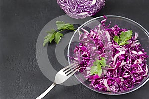 Salad of fresh red cabbage with herbs, half a fresh head of cabbage, 1 plate of vegetable vitamin salad on a black background