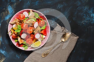 Salad of fresh vegetables with Arabic bread fattoush on a blue background, top view. Copy space.