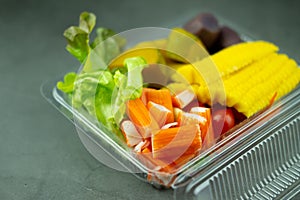 Salad of fresh vegetables and healthy fruit in clear plastic box