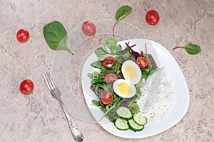 Salad of green vegetables, tomato and rice in a white plate. Rice with vegetables and eggs on a white plate