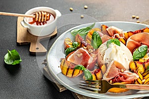 Salad with grilled peaches, mozzarella, prosciutto ham, basil, for wine. top view. place for text