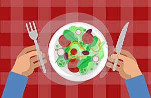 Salad and hands holding knife and fork