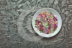 Salad, healthy food. Red cabbage salad. Fresh vegetable salad with purple cabbage, white cabbage, salad, carrot in a dark clay bow