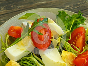 Salad with herbs, seasonal  spring    tomatoes on a wooden background
