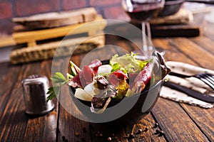 salad with jamon and red wine on wooden table photo